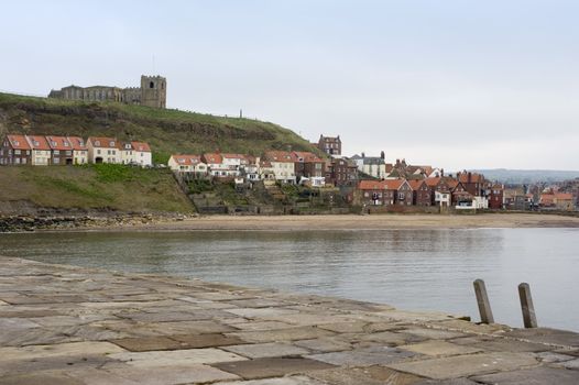 View across the River Esk of the Tate Hill Beach and waterfront with Tate Hill and St Marys Church behind, Whitby, North Yorkshire, UK