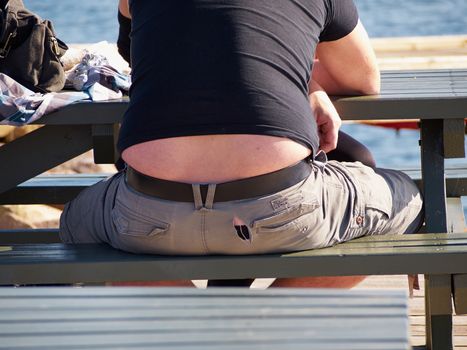 Obesity fat mature man with overweight stomach sitting on a bench