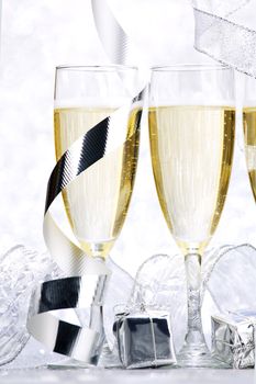 Glasses of champagne and christmas gifts on silver background