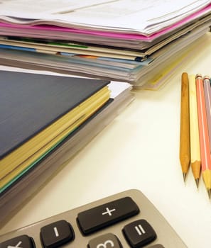 Office supplies on the table, including paper, pencil, calculator and workbook files.                               