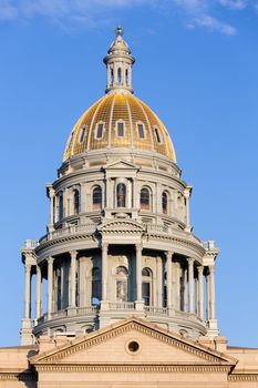 The gold leaf covered dome of the State Capitol Dome in Denver Colorado shortly after sunrise