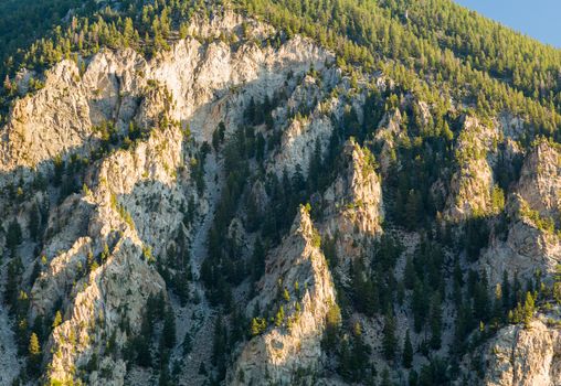 Steep jagged spikes of  chalk white cliffs of Mount Princeton near Buena Vista in Colorado shortly after sunrise as the sun first lights the mountainside