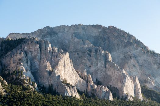 Steep jagged spikes of  chalk white cliffs of Mount Princeton near Buena Vista in Colorado shortly after sunrise as the sun first lights the mountainside