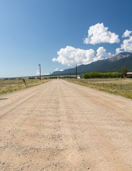 Long straight dirt graded road across open countryside to distant mountains in Colorado