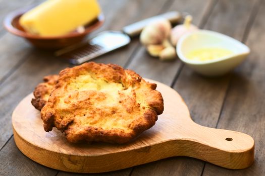 Freshly prepared traditional Hungarian deep fried flat bread called Langos made of a yeast dough, which is usually eaten with garlic, grated cheese and/or sour cream, or just simply salted (Selective Focus, Focus one third into the langos) 

 