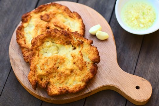 Freshly prepared traditional Hungarian deep fried flat bread called Langos made of a yeast dough, which is usually eaten with garlic, grated cheese and/or sour cream, or just simply salted (Selective Focus, Focus in the middle of the langos) 

 