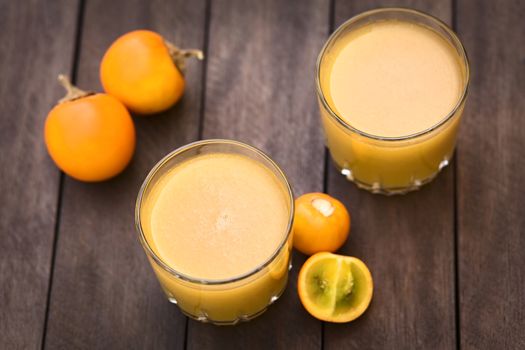 Freshly prepared juice out of Naranjilla or Lulo fruits (lat. Solanum quitoense) with fruits on the side (Selective Focus, Focus in the middle of the first juice) 