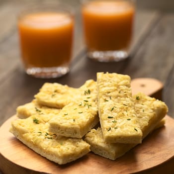 Fresh homemade garlic and cheese sticks made of a yeast dough served on wooden board, sprinkled with fresh thyme leaves (Selective Focus, Focus one third into the upper garlic stick)