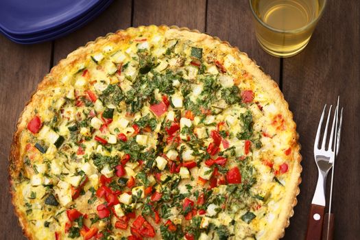 Homemade vegetarian quiche with zucchini, red bell pepper and parsley in baking dish (Selective Focus, Focus in the middle of the quiche)