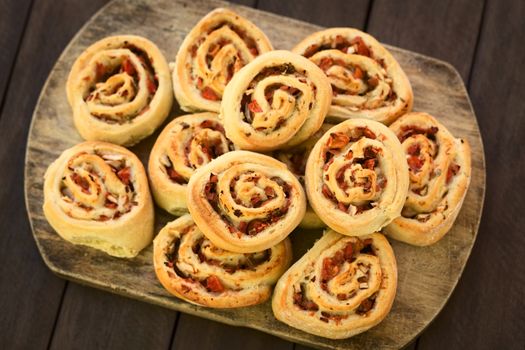 Freshly baked homemade rolls filled with tomato, ham and herbs on wooden board (Selective Focus, Focus on the first two rolls on the top) 