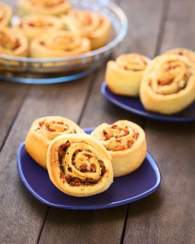 Freshly baked homemade rolls filled with tomato, ham and herbs on blue plate (Selective Focus, Focus on the middle and lower part of the first roll) 