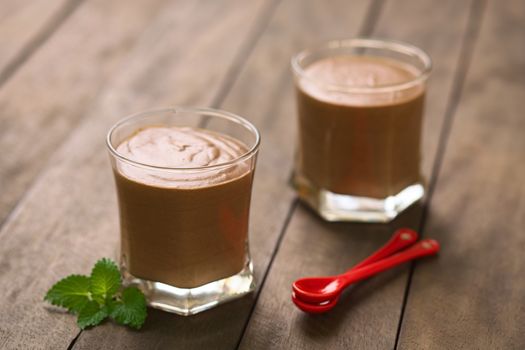 French dessert called Mousse au Chocolat, made of melted chocolate, egg, cream and sugar served in glasses with two small spoons on the side (Selective Focus, Focus on the front rim of the first glass)