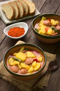 Two bowls of the Hungarian dish called Paprikas Krumpli (Potato with Paprika), a stew made of potato, onion, pepper, tomato and sausage, seasoned with the Hungarian paprika and salt (Selective Focus, Focus in the middle of the dish in the first bowl) 