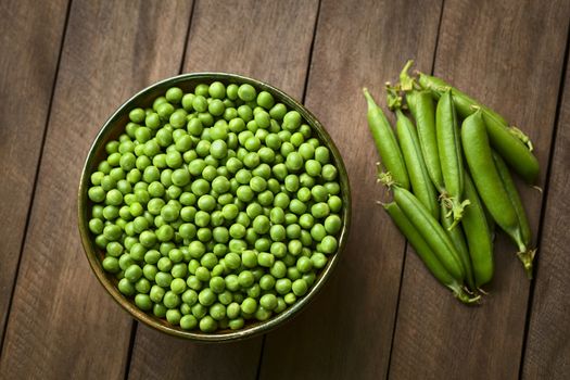 Peas (lat. Pisum sativum) in bowl with closed peapods on the side (Selective Focus, Focus on the lower half of the peas in the bowl)