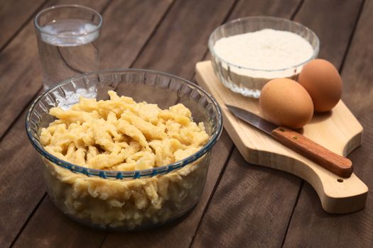 Glass bowl with homemade Hungarian Nokedli or Galuska, a type of egg noddle, made by cutting the soft dough on a wooden board into boiling water (Selective Focus, Focus into the middle of the noodles) 
 