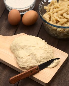 Preparing Hungarian Nokedli or Galuska out of an egg-flour dough. The dough gets cut in small pieces into boiling water, and is served as side dish (Selective Focus, Focus one third into the image) 