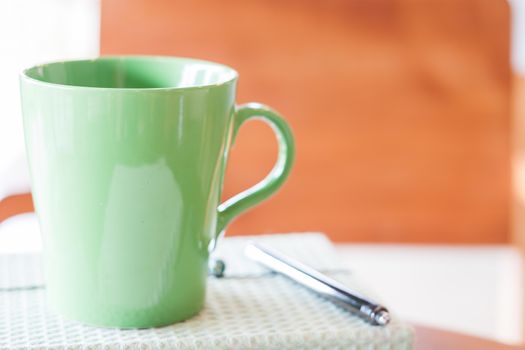 Closeup green mug with pen and notebook, stock photo