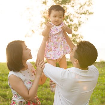Portrait of happy Asian family playing together at outdoor park during summer sunset.