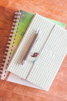 Top view of pen on two notebooks on wooden table, stock photo