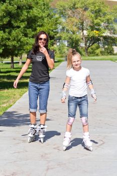 Photo of mother and daughter on roller skates in summer