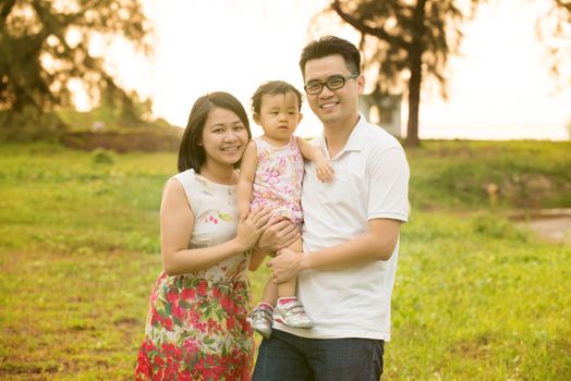 Happy Asian family portrait. Outdoor playing time during summer sunset.