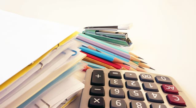 Office supplies on the table, including paper, pencil, calculator and workbook files.                                