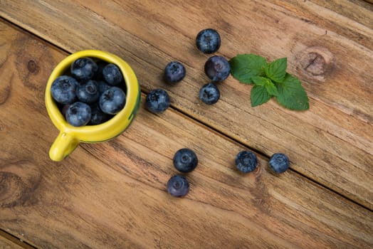 Fresh blueberries on kitchen wooden table with yellow pot