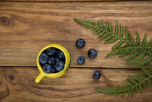 Fresh blueberries on kitchen wooden table with yellow pot