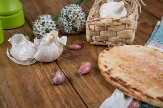 Fresh garlic bulb and naan bread on kitchen table