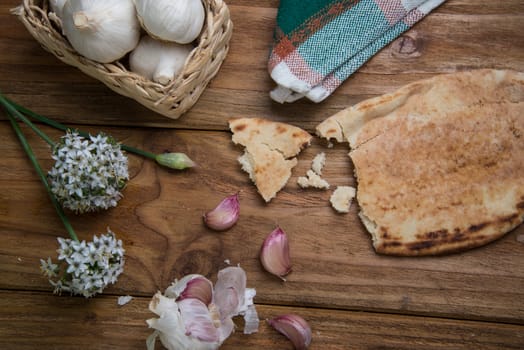 Fresh garlic bulb and flowers and naan bread on kitchen table