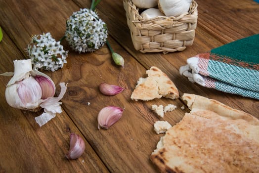 Fresh garlic bulb and flowers and naan bread on kitchen table