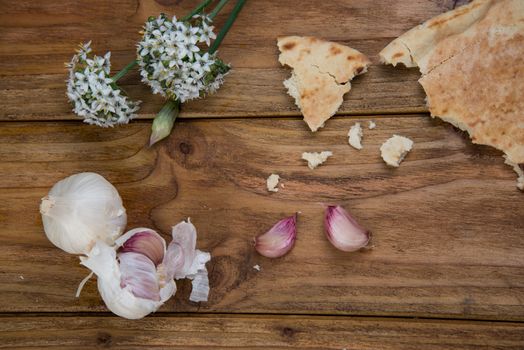 Fresh garlic bulb and flowers and naan bread on kitchen table