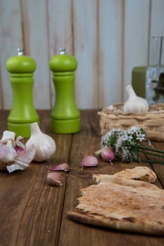 Fresh garlic bulb and flowers and naan bread on kitchen table