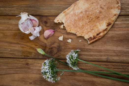 Fresh garlic bulb and flowers and naan bread on kitchen table