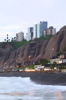 LIMA, PERU - APRIL 2, 2012: The steep coast and the lighthouse of the district of Miraflores as seen from the waterside in the evening on April 2, 2012 in Lima, Peru. Miraflores is a modern and upscale district, which attracts many tourists.