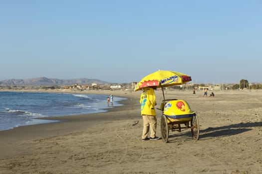 LOS ORGANOS, PERU - AUGUST 30, 2013: Unidentified person selling ice cream in a cart on the sandy beach on August 30, 2013 in Los Organos, Peru. Los Organos is a small town in Northern Peru, close to the touristy beach town of Mancora.
