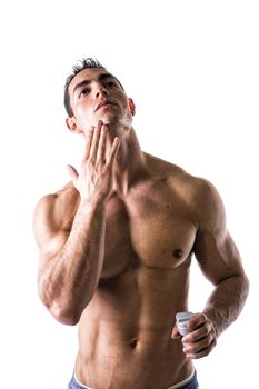 Man with muscular chest and abs applying shaving cream on his face on white background