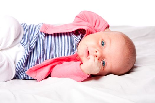 Cute baby girl with blue eyes laying in soft crib.