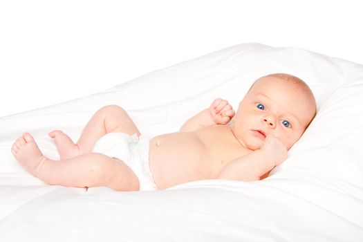 Cute baby infant laying on white pillow wearing diaper.