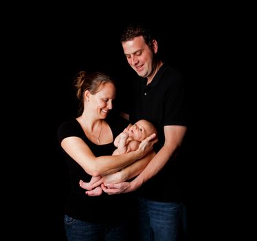 Happy smiling mother father holding baby infant, on black.