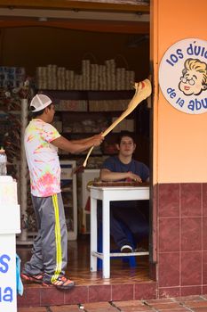 BANOS, ECUADOR - FEBRUARY 25, 2014: Unidentified young men preparing the traditional handcrafted taffy called Melcocha made from cane sugar at the shop Los Dulces de la Abuela on Ambato Street on February 25, 2014 in Banos, Ecuador.