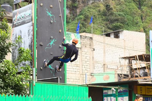 BANOS, ECUADOR - FEBRUARY 25, 2014: Unidentified person practicing abseiling for canyoning on a climbing wall on February 25, 2014 in Banos, Ecuador. Banos is a small touristy town offering a lot of outdoor activities, such as canyoning (abseiling a waterfall).