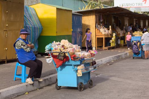 BANOS, ECUADOR - FEBRUARY 26, 2014: Unidentified woman selling sweets from a cart on Luis A. Martinez street on February 26, 2014 in Banos, Ecuador. She is selling also melcocha, a traditional taffy from Banos made of sugarcane. 