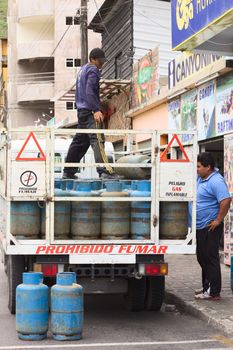 BANOS, ECUADOR - FEBRUARY 28, 2014: Unidentified people at a truck full of gas bottles on the 16 de Diciembre Street on February 28, 2014 in Banos, Ecuador. In Ecuador, people use gas for cooking and heating water. The government is planning to change this until 2016, where cooking and heating water will be done electrically.