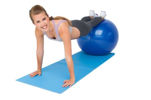 Portrait of a fit young woman stretching on fitness ball over white background