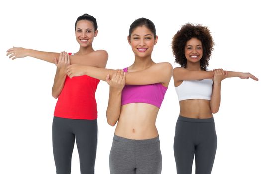 Portrait of three sporty young women stretching hands over white background