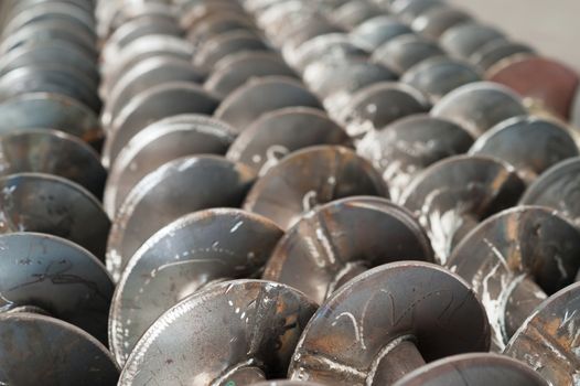 Unfinished screw conveyor parts at a factory. Very shallow depth of field with the nearest part of the screws in focus.