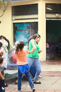 BANOS, ECUADOR - MARCH 2, 2014: Unidentified young woman being sprayed with foam at carnival on Ambato Street on March 2, 2014. It is officially forbidden to use foam or water to spray others, but still many are using the sprays and it is being sold in many shops. (Selective Focus, Focus on the woman in green t-shirt)