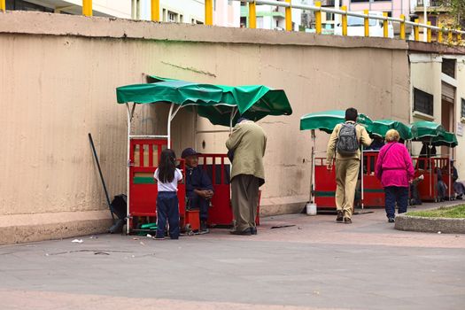 AMBATO, ECUADOR - APRIL 9, 2014: Unidentified people at shoe cleaning booths in 12 de Noviembre Park on April 9, 2014 in Ambato, Ecuador. Ambato is the capital of the Tungurahua Province in Central Ecuador.
