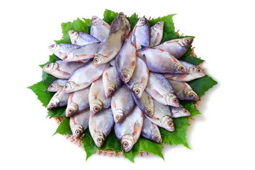 Carp and greens on a round dish. Presented on a white background.